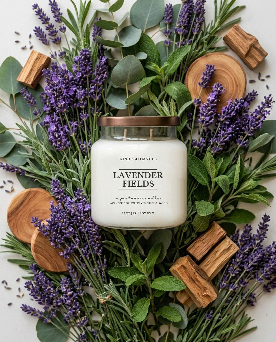 Soy Candle labeled 'Lavender Fields' surrounded by lavender flowers and greenery on a white background